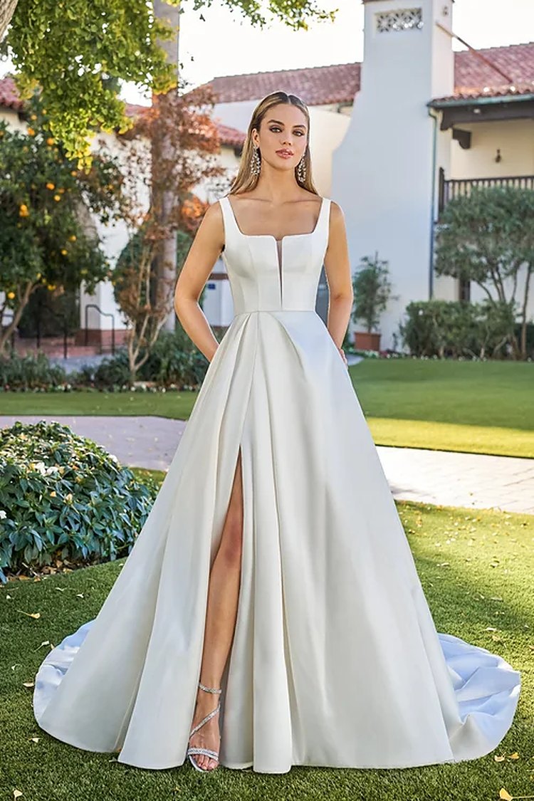 Model in an ivory satin A-line bridal gown with a square neckline and front slit
